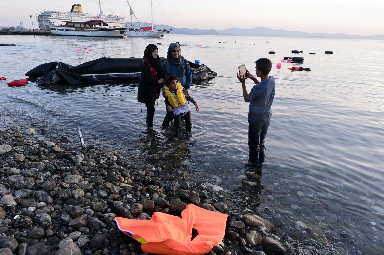 Syrian migrants take a picture after their safe arrival on an overcrowded dinghy to the coast of the southeastern Greek island of Kos from Turkey, on August 15, 2015. A ferry boat has been sent by the Greek government to the resort of Kos to speed up the registration process of hundreds of Syrian refugees, docked on August 14 afternoon at the harbour. The Eleftherios Venizelos will stay moored in Kos for some two weeks, during which time authorities will register newcomers to the island, which is already overflowing with refugees and migrants. AFP PHOTO /LOUISA GOULIAMAKI