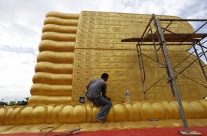 epa05550006 A picture made available 21 September 2016 shows a Thai workman painting the feet of a giant reclining golden Buddha, at a Buddhist temple named Wat Phranon Laem Pho, on Ko Yo island, Songkhla province, southern Thailand, 18 September 2016. Thailand's many Buddhist temples and large Buddha statues are among attractions highlighted for the Kingdom's healthy tourism industry, which is expected to reach a record this year of more than 32 million arriving tourists. Despite Thailand's political situation and a recent spate of bombings, Thai tourism continues to surge. United Nations World Tourism Day celebrations will be held in Thailand and across the world on 27 September 2016.  EPA/BARBARA WALTON