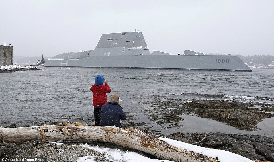 FILE - In this March 21, 2016 file photo, Dave Cleaveland and his son, Cody, photograph the USS Zumwalt as it passes Fort Popham at the mouth of the Kennebec River in Phippsburg, Maine, as it heads to sea for final builder trials. The ship is so stealthy that the U.S. Navy resorted to putting reflective material on its halyard to make it visible to mariners during the trials. (AP Photo/Robert F. Bukaty, File)