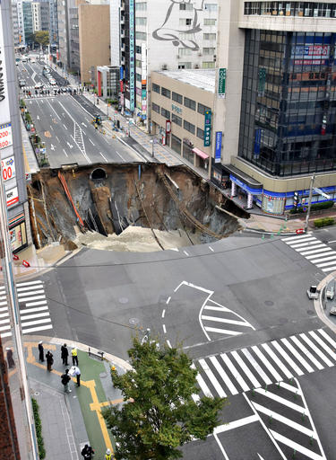 A massive shinkhole is created in the middle of the business district in Fukuoka, southern Japan Tuesday, Nov. 8, 2016. Parts of a main street have collapsed in the city, creating a huge sinkhole and cutting off power, water and gas supplies to parts of the city. Authorities said no injuries were reported from Tuesday's pre-sunrise collapse in downtown Fukuoka. (Kyodo News via AP)