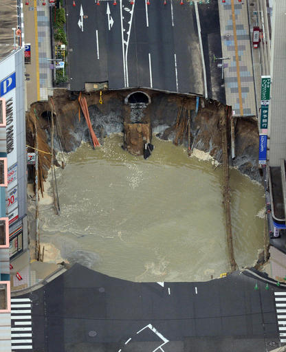 A massive shinkhole is created in the middle of the business district in Fukuoka, southern Japan Tuesday, Nov. 8, 2016. Parts of a main street have collapsed in the city, creating a huge sinkhole and cutting off power, water and gas supplies to parts of the city. Authorities said no injuries were reported from Tuesday's pre-sunrise collapse in downtown Fukuoka. (Kyodo News via AP)