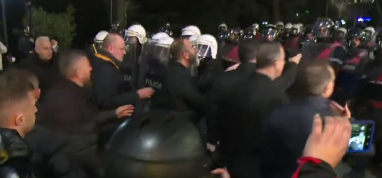 Një gardh në rrugë nga forcat speciale të Policisë, pengojnë marshimin. Ka përplasje
